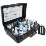 A black carrying case labeled Salt Water Aquaculture Outfit Model AQ-4 - 3635-05, filled with small bottles, droppers, test tubes, and color cards for water testing. The case lid displays instructions, with a separate color chart beside the kit.