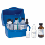 Una caja de plástico azul etiquetada como Tolcide PS Biocides Test Kit - 4-8776-01 contiene varias botellas y cuentagotas con soluciones científicas, como buffer de borato, solución PS, solución de yodo e indicador de almidón dispuestos ordenadamente delante.