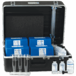 Un estuche negro contiene los kits de prueba de macronutrientes del suelo - 5928-01, envases químicos azules, botellas de plástico transparente, tubos de ensayo en un soporte, un inserto de espuma negra y otros suministros de laboratorio para análisis de agua. El caso está abierto y ordenado.