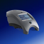 A modern, gray laboratory device with a touchscreen display sits on a blue gradient background. The device has a sleek, curved design and appears to be used for scientific or medical purposes.